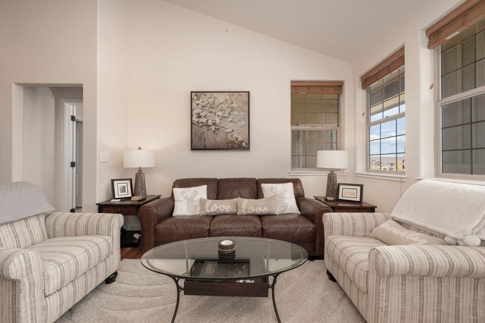 Sink into plush seating around your glass coffee table, where love-themed pillows invite cozy conversations in this bright, welcoming living space.