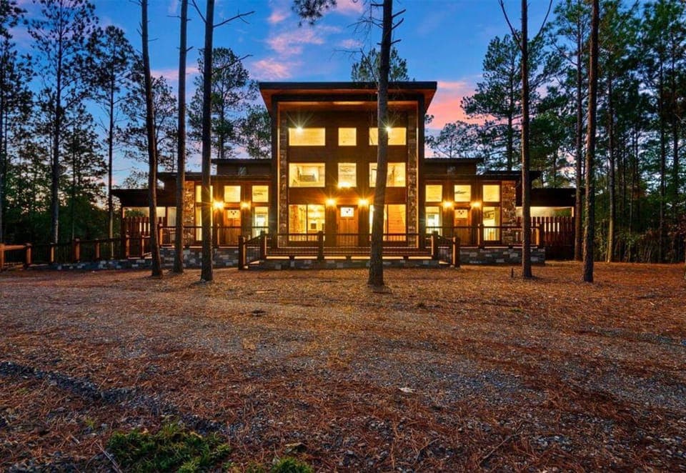 The cabin’s glowing lights create a magical setting, blending modern design with natural charm.