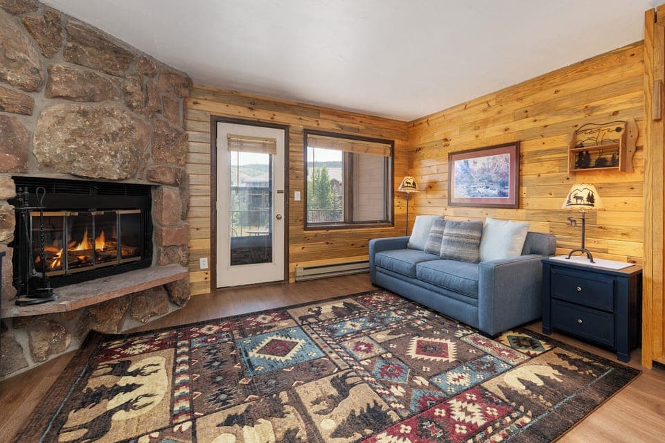 Cozy up by the crackling stone fireplace at 564 SilverCreek Inn in this rustic living room, where warm wood walls and mountain charm create the perfect retreat.