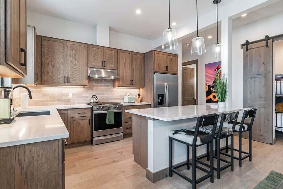 - Contemporary kitchen with rich wood cabinetry and stainless steel appliances
- Spacious island doubles as a breakfast bar with stylish overhead lighting
- Layout offers plenty of counter space for cooking and gathering