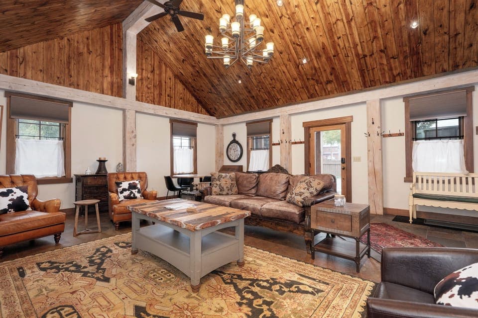 Relax in your rustic-chic living room with soaring wood ceilings, leather seating, and warm lighting creating the perfect cozy retreat.