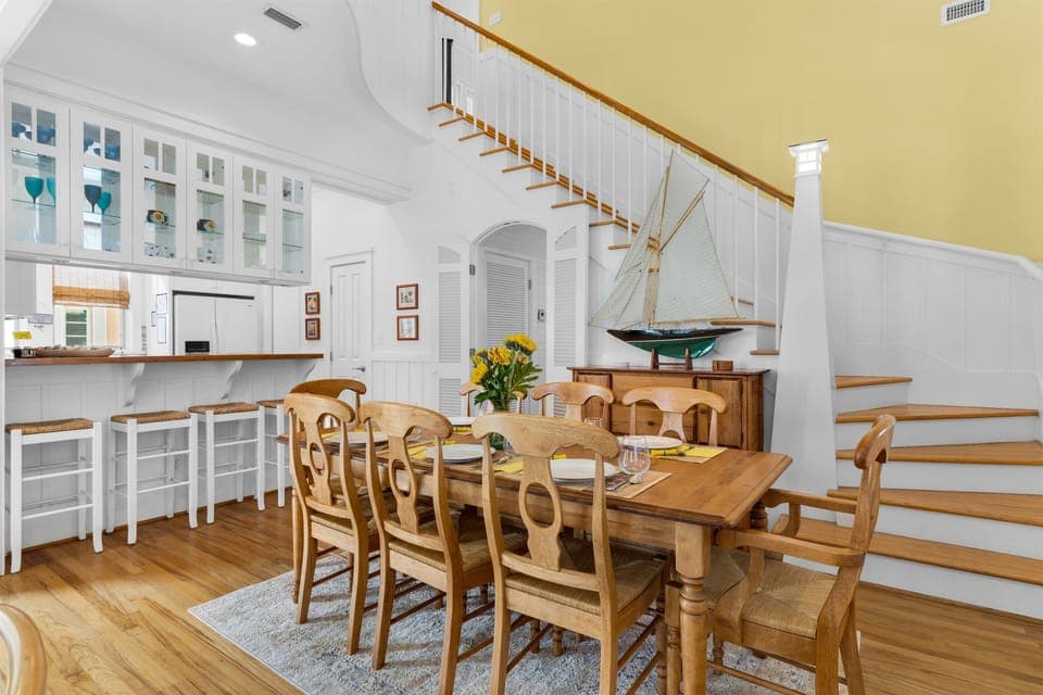 Step into this bright coastal dining space where warm wood tones meet crisp white cabinetry, creating the perfect spot for memorable meals together.