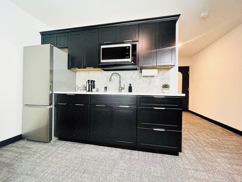 Stylish kitchen with dark cabinetry, stainless steel appliances, and a well-appointed coffee station for your morning needs.

