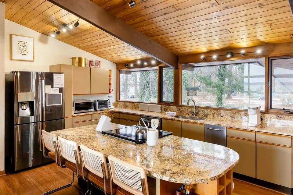 The kitchen offers a spacious, modern design with granite countertops, state-of-the-art appliances, and a large island perfect for meal prep or casual dining, all while enjoying scenic views through expansive windows.