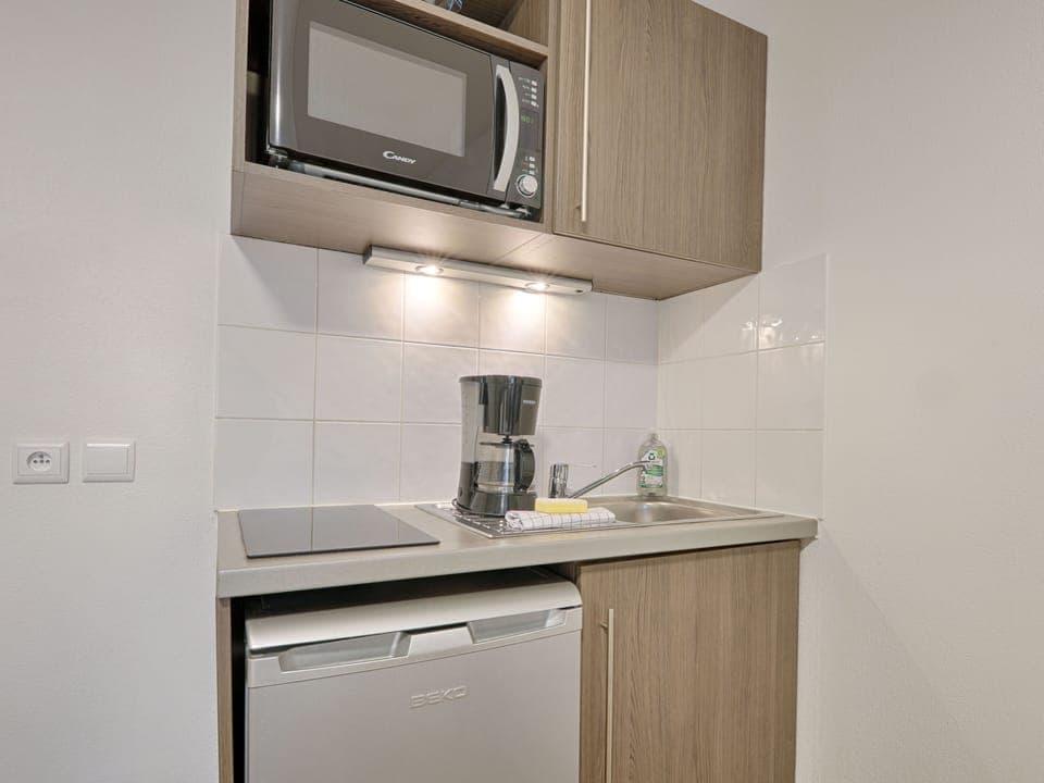 Well-appointed kitchenette within the studio, featuring a microwave, electric hob, and compact fridge for effortless meal preparation.