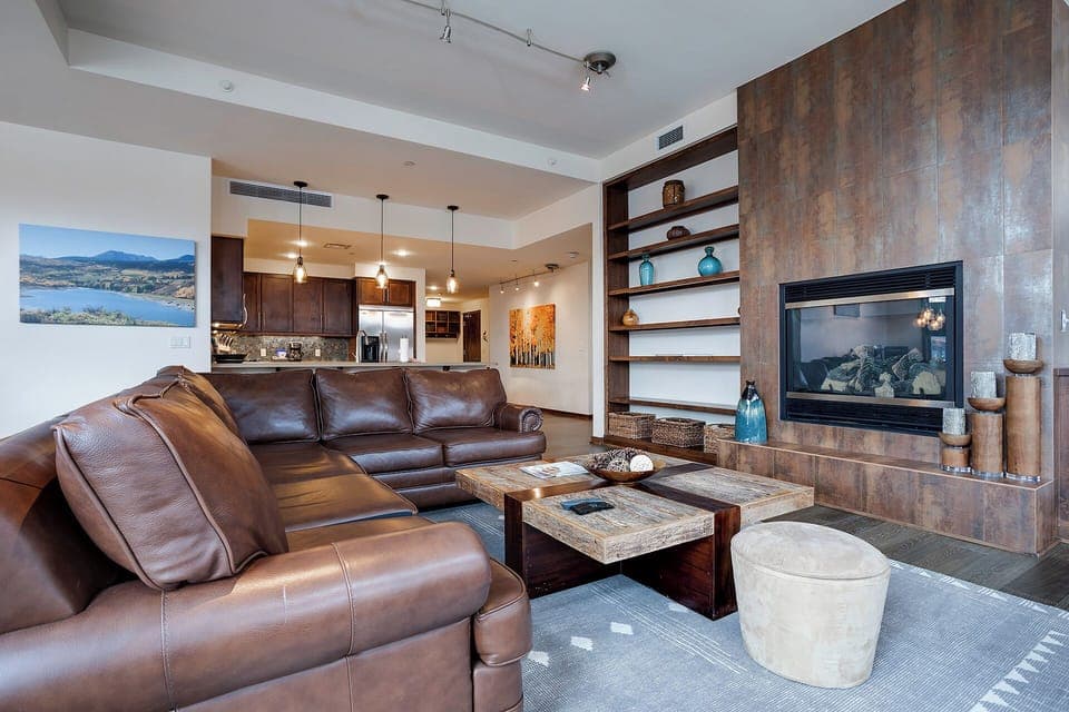 Sink into plush leather seating by your cozy fireplace, where warm wood tones create the perfect retreat after mountain adventures.