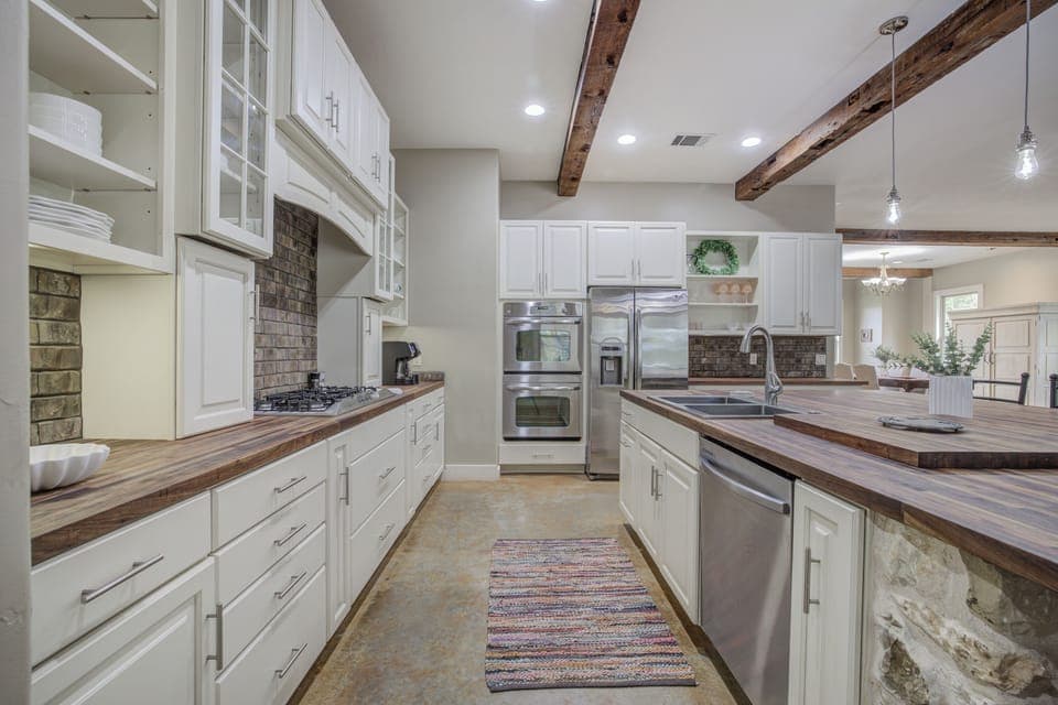 Fully equipped kitchen with stainless steel appliances, rustic beams, and ample counter space—perfect for cooking and gathering.
