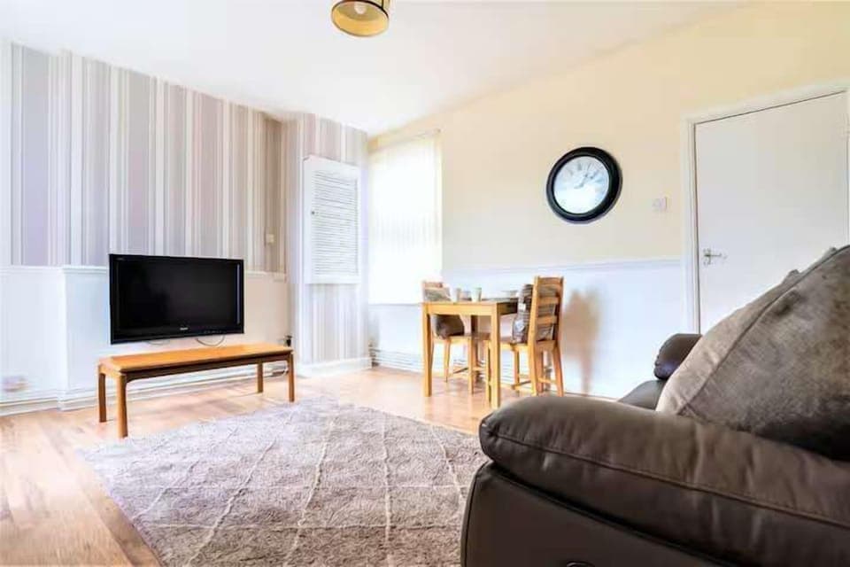 Bright cosy living room with 2 person sofa, table and chairs and Tv