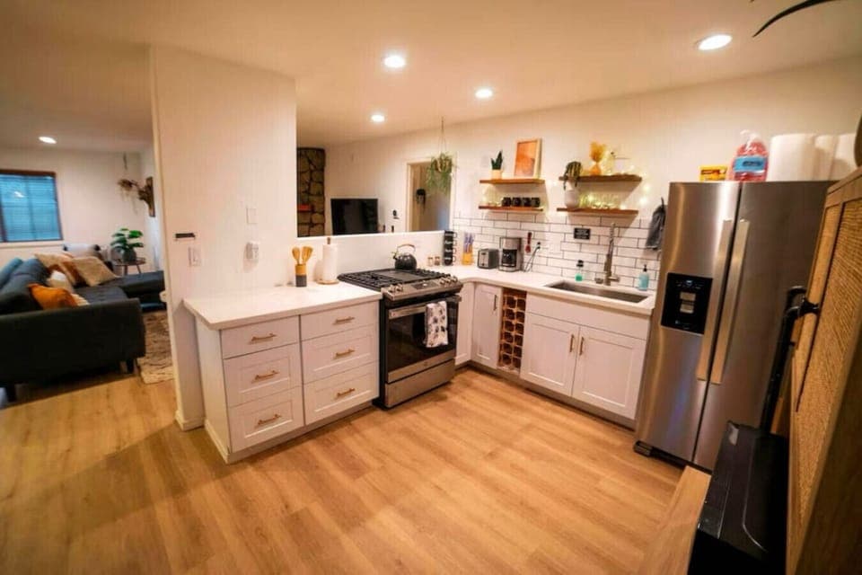 Fully equipped stylish kitchen with open shelving and stainless steel appliances.