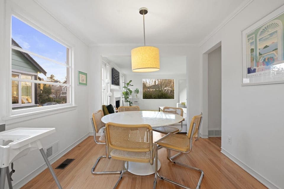DINING: This bright dining area seats six and includes a high chair for little ones. A cozy pendant light and large windows create a warm, inviting atmosphere.
