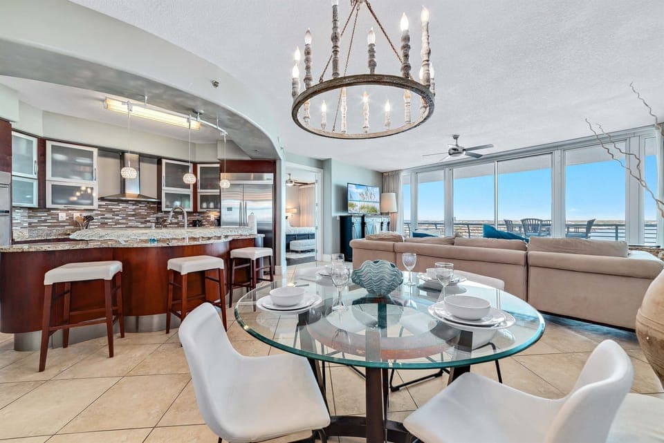 Gather around the beautifully appointed dining table, where every detail, from the textured placemats to the delicate glassware and serene colored plates, creates an inviting atmosphere for memorable meals.