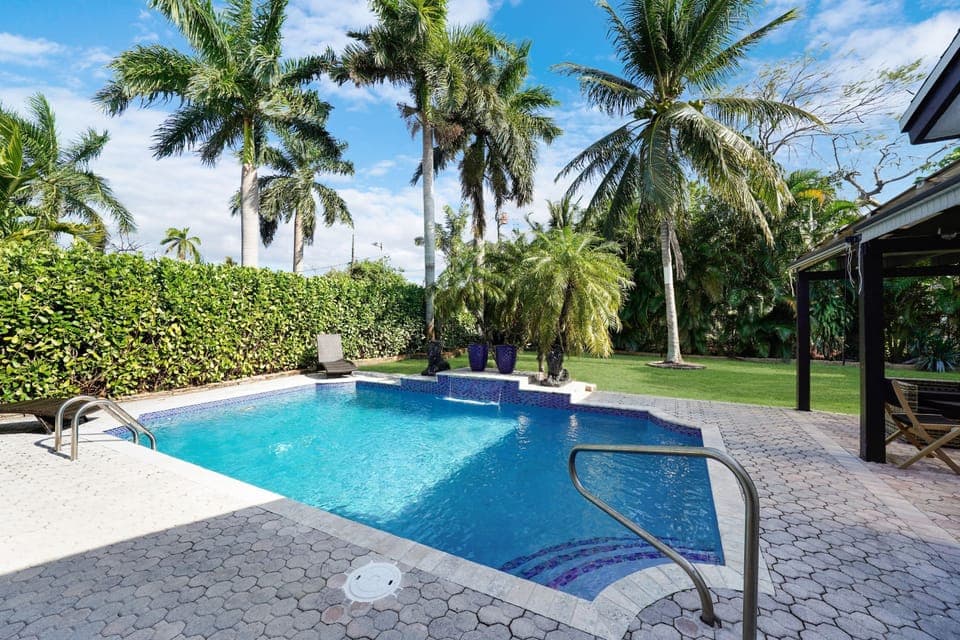 This lush, tropical sanctuary features a large, sparkling pool with cascading waterfalls, creating a tranquil, resort-like ambiance.