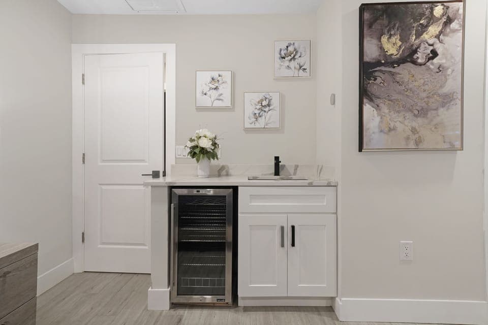 A beautifully designed wet bar with a built-in wine cooler, sleek cabinetry, and artistic accents, perfect for entertaining or enjoying a quiet drink.