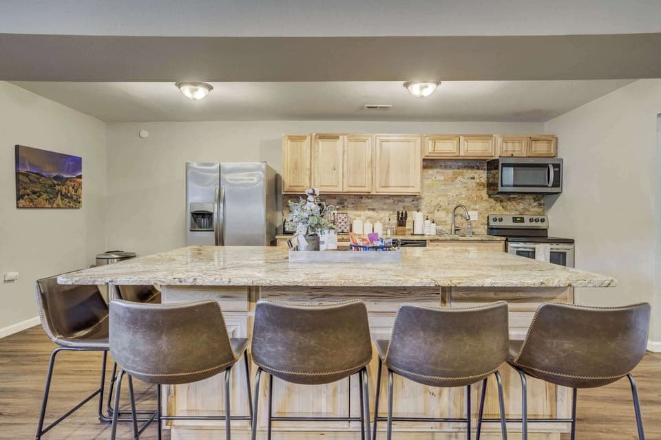 The fully equipped kitchen features stainless steel appliances, a spacious island with bar seating, and a stylish stone backsplash. Perfect for preparing delicious meals while staying connected with family and friends.





