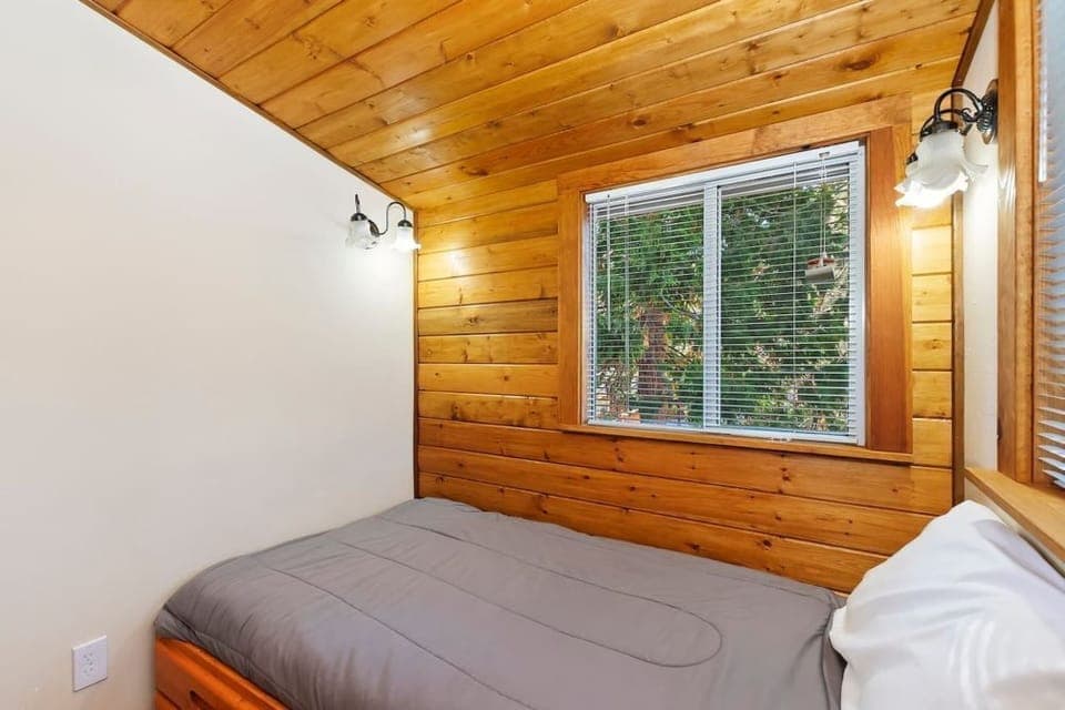 "Unwind in our charming bedroom with wooden walls, natural light, and a cozy bed, creating a warm and inviting retreat