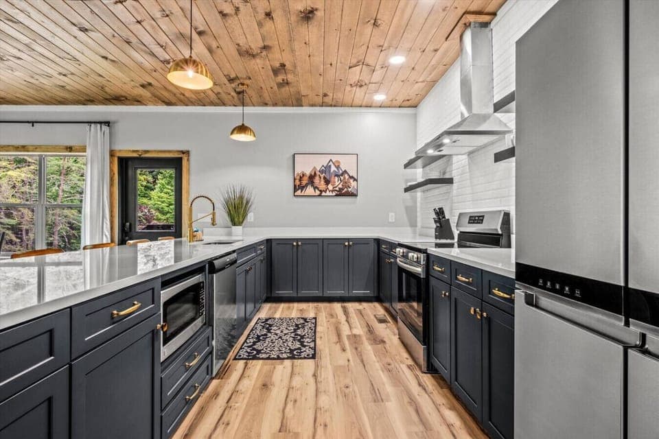 Create meals with ease in this gourmet kitchen, featuring navy cabinetry, brass hardware, stainless appliances, and plenty of counter space for everyone to join in.