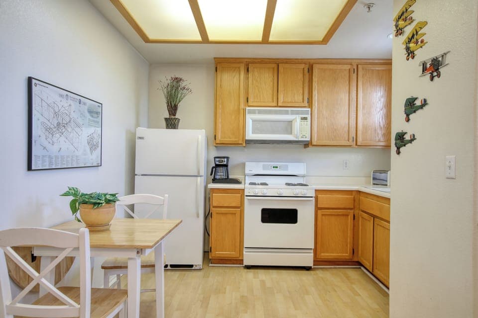 This cozy kitchen features warm wood cabinetry, a full-size refrigerator, gas stove, microwave, and a quaint dining nook, perfect for enjoying meals in a bright, inviting space.