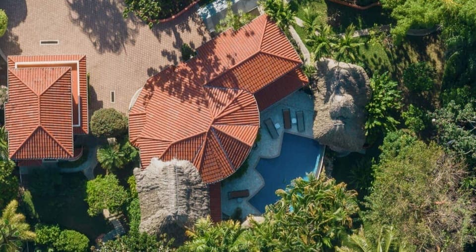 Overhead view of villa estate with terracotta roof and lagoon-style pool.