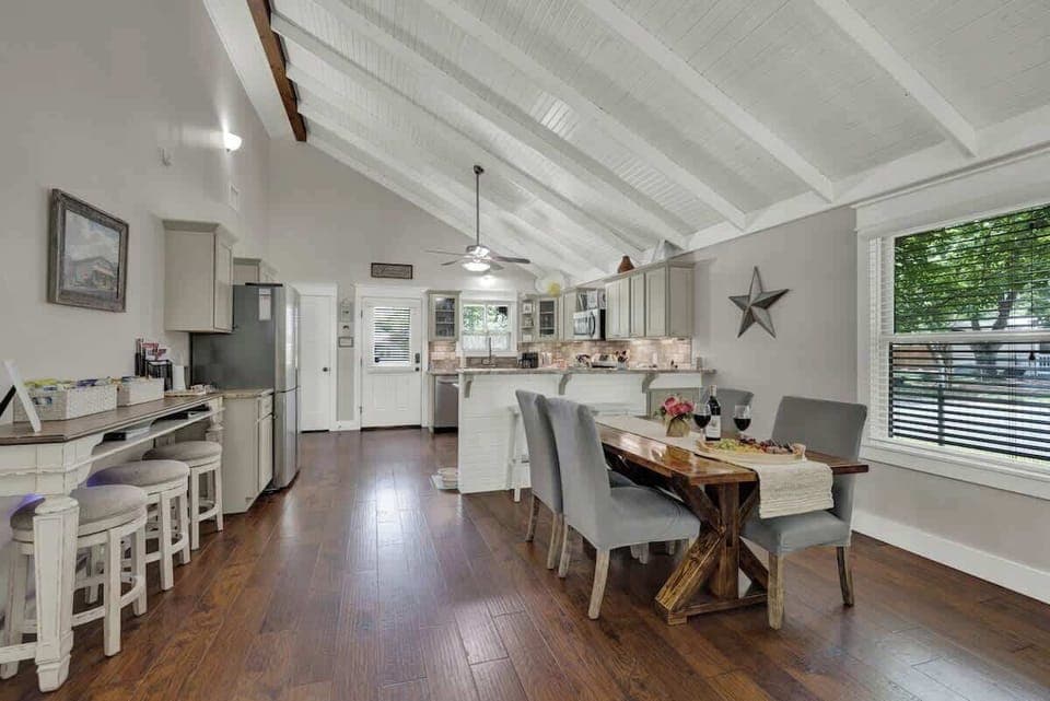 The dining table comfortably seats four, with additional seating available at the kitchen counter and the standalone bar.