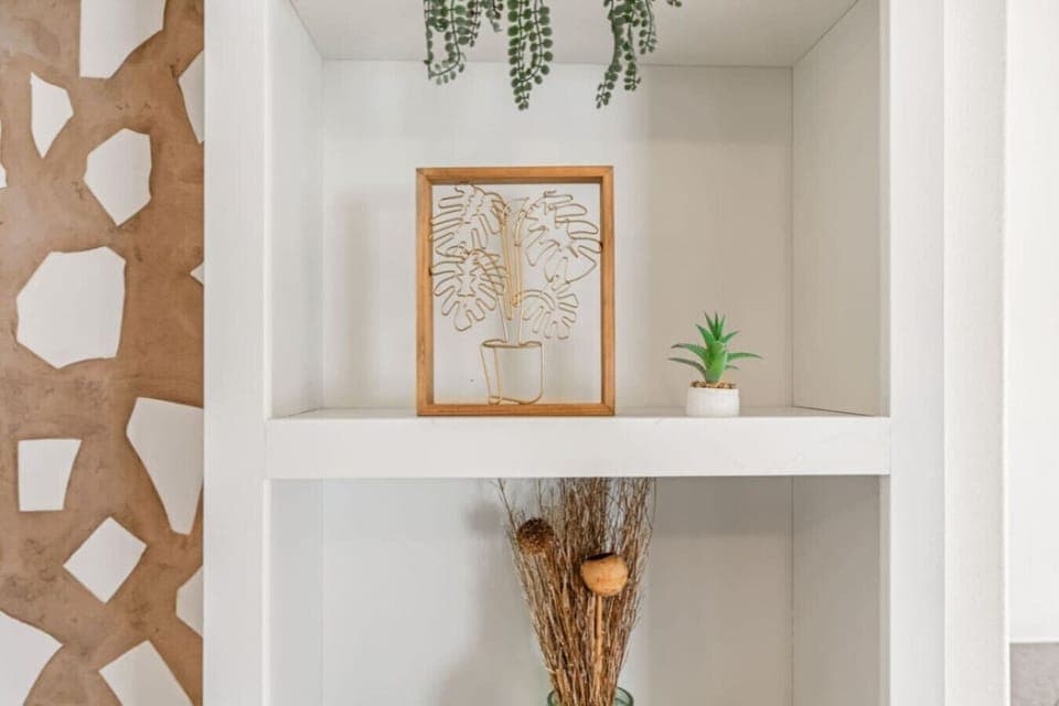 Built-in shelves styled w/ art, greenery & warm textures that add personality to the space.