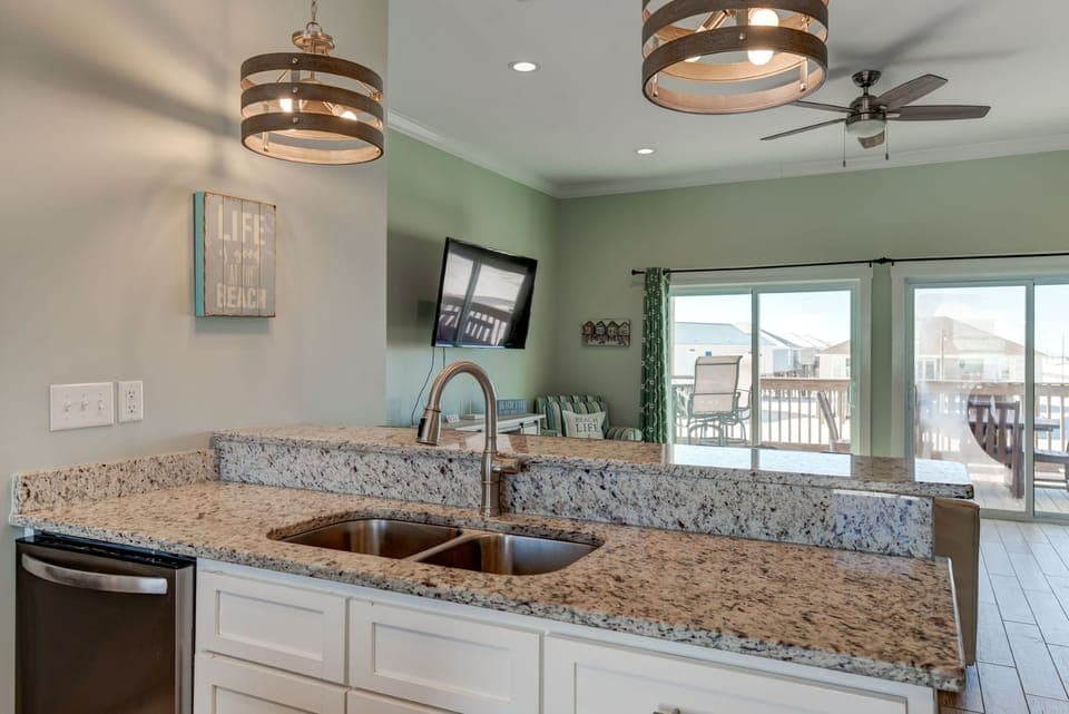 Your spacious kitchen features granite countertops, modern pendant lighting, and opens to the balcony where ocean views await.