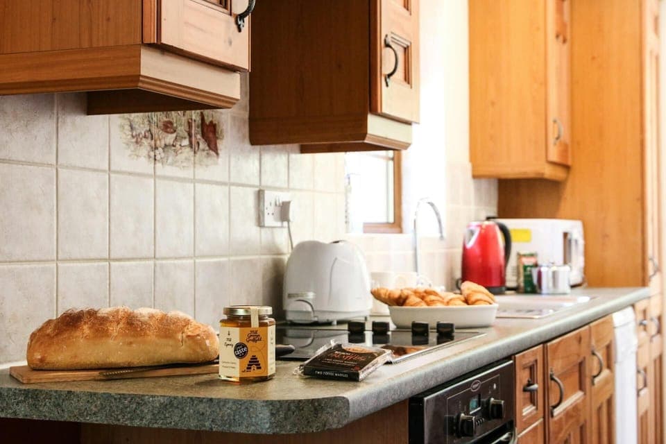 Kitchen with cooker, microwave, toaster, kettle, sink, bread and honey