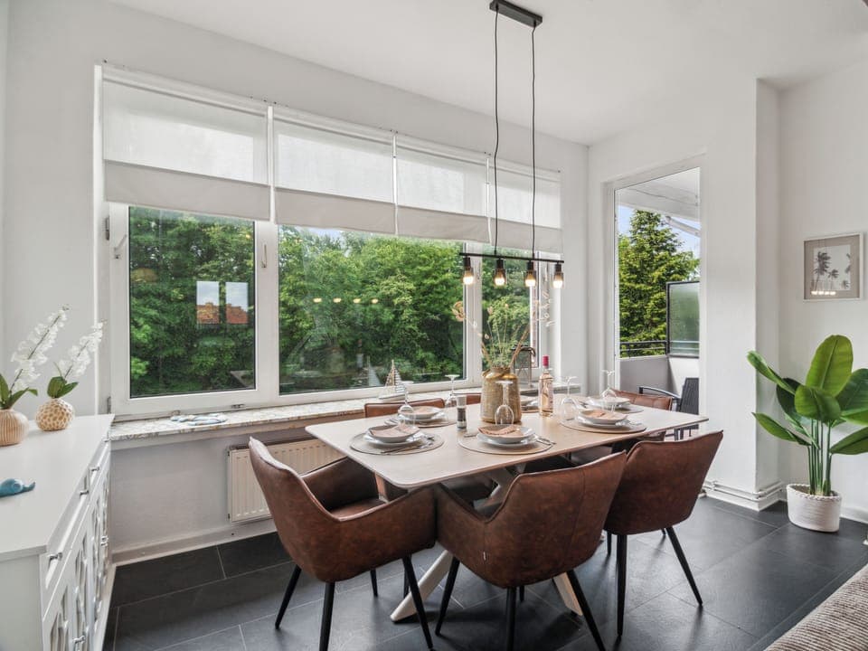 Ein großzügiger, lichtdurchfluteter Essbereich mit stilvoller Einrichtung und Ausblick ins Grüne bietet den perfekten Ort für gemeinsame Mahlzeiten.