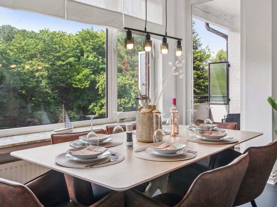 Ein heller Essbereich mit großem Tisch, eleganter Dekoration und Blick ins Grüne lädt zu gemeinsamen Mahlzeiten in gemütlicher Atmosphäre ein.