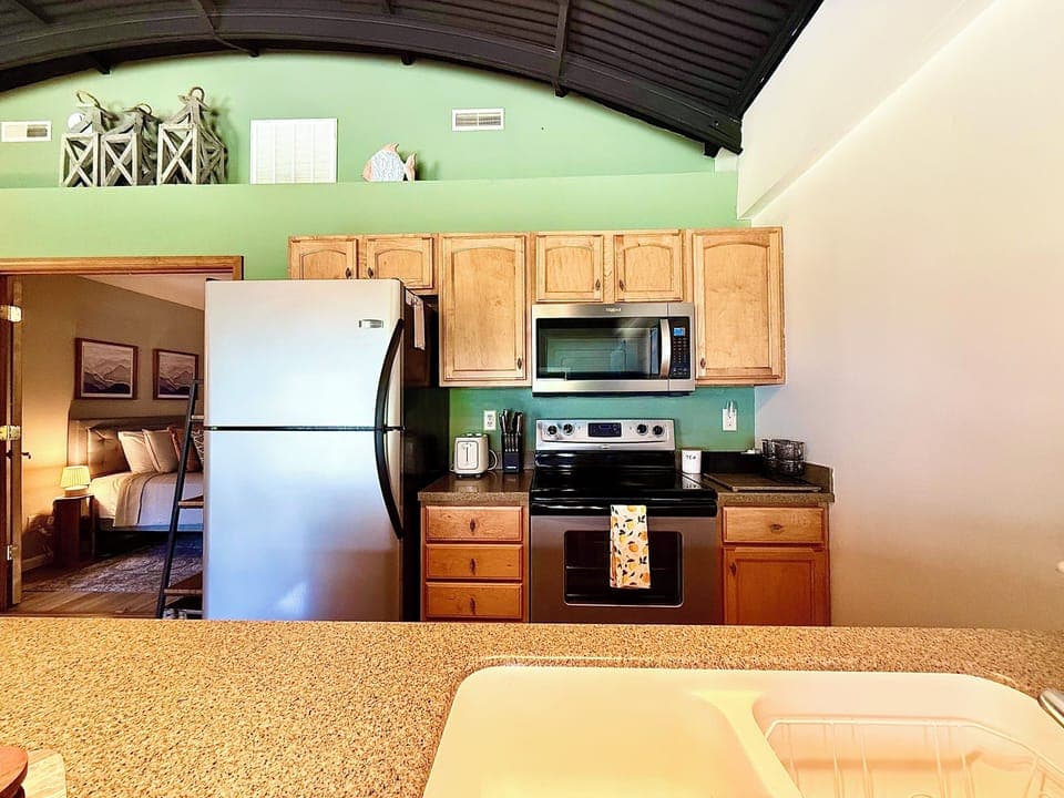 Fully Equipped Kitchen
Prepare meals with ease in this fully stocked kitchen featuring stainless appliances, a full-size fridge, microwave, oven, and bar seating—perfect for gathering and dining together.