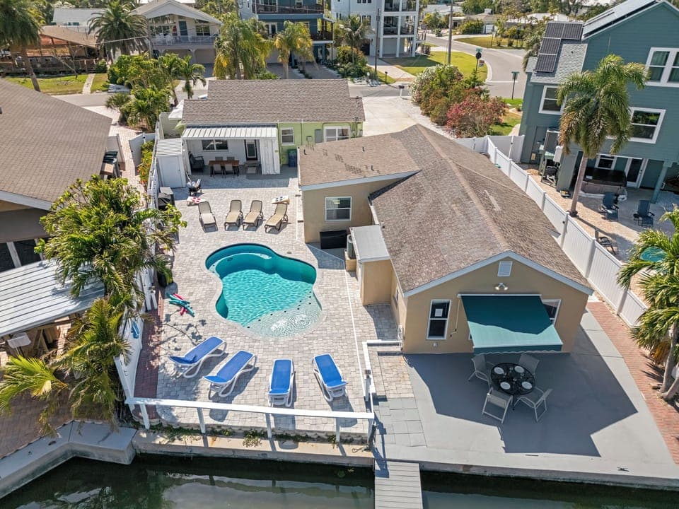 Aerial view of bayfront home with pool, beach access, nearby park, and dining.