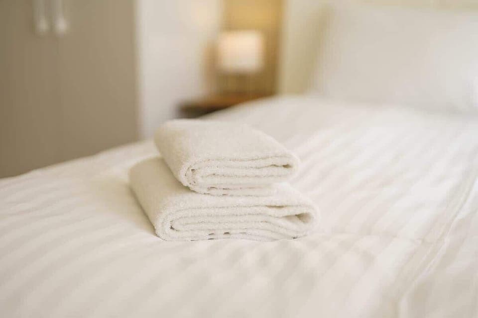 Soft, white towels are folded neatly on the bed, adding a touch of hospitality. The room appears clean and inviting for guests.