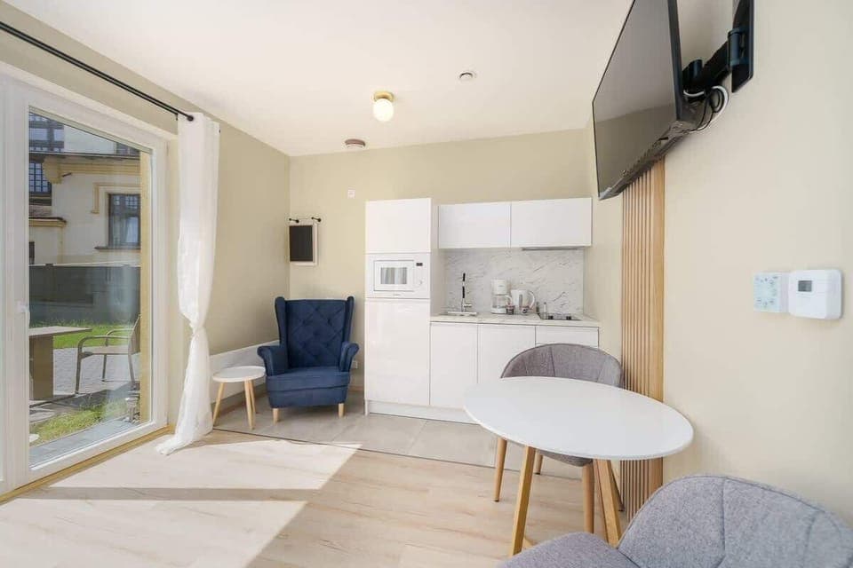 A different view of the same bedroom, showcasing the neatly made bed with soft white linens and a window providing ample daylight.