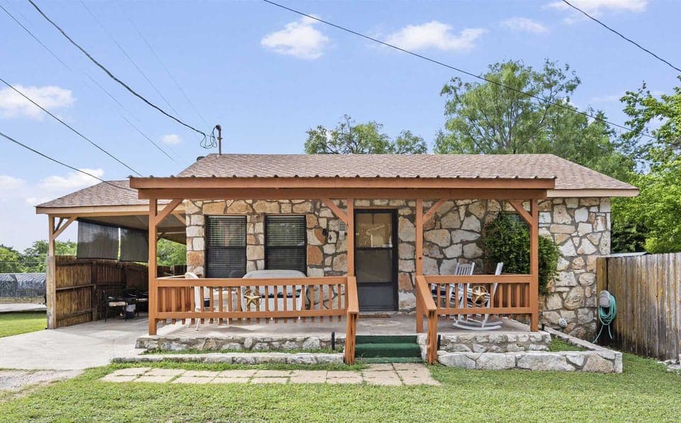 A cozy stone vacation rental with a charming front porch, perfect for a relaxing getaway.