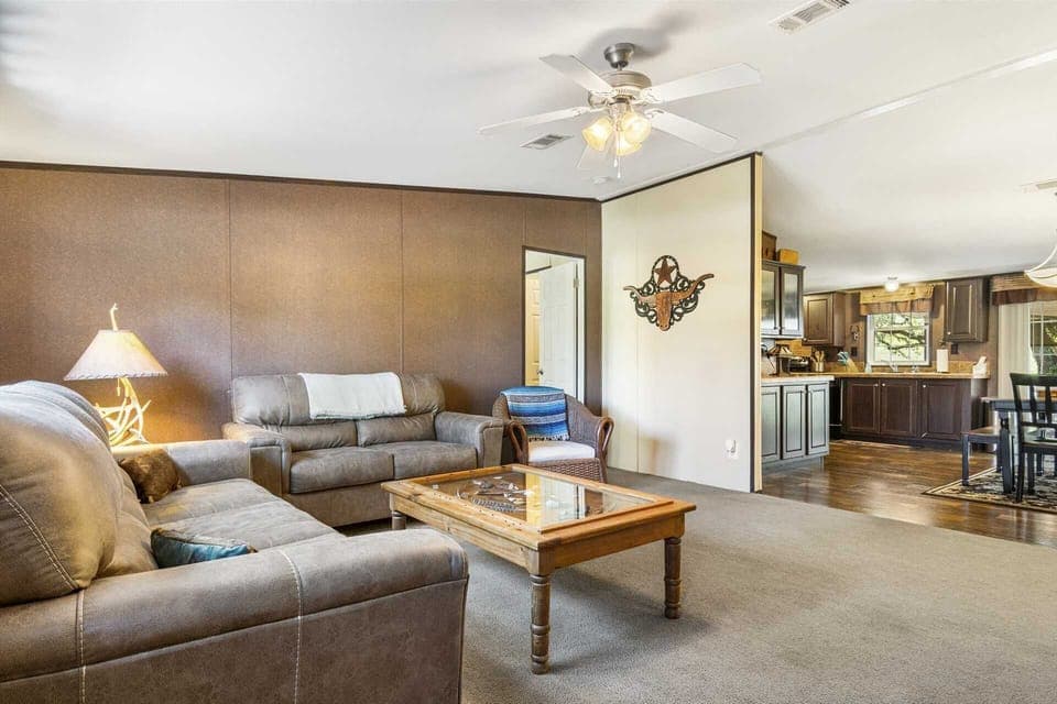 Unwind in comfort! This spacious living area flows into the kitchen, perfect for relaxing and socializing.