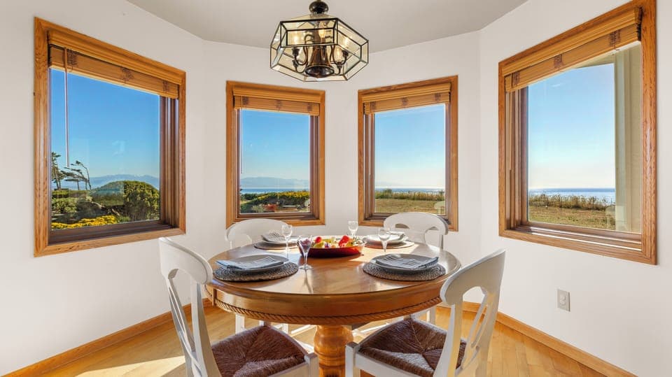 Cozy kitchen nook with a small table for four, set near windows that showcase beautiful water views.