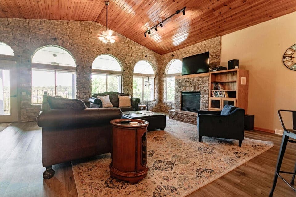 Cozy living room with vaulted ceilings, stone fireplace, and natural light—perfect for relaxing.