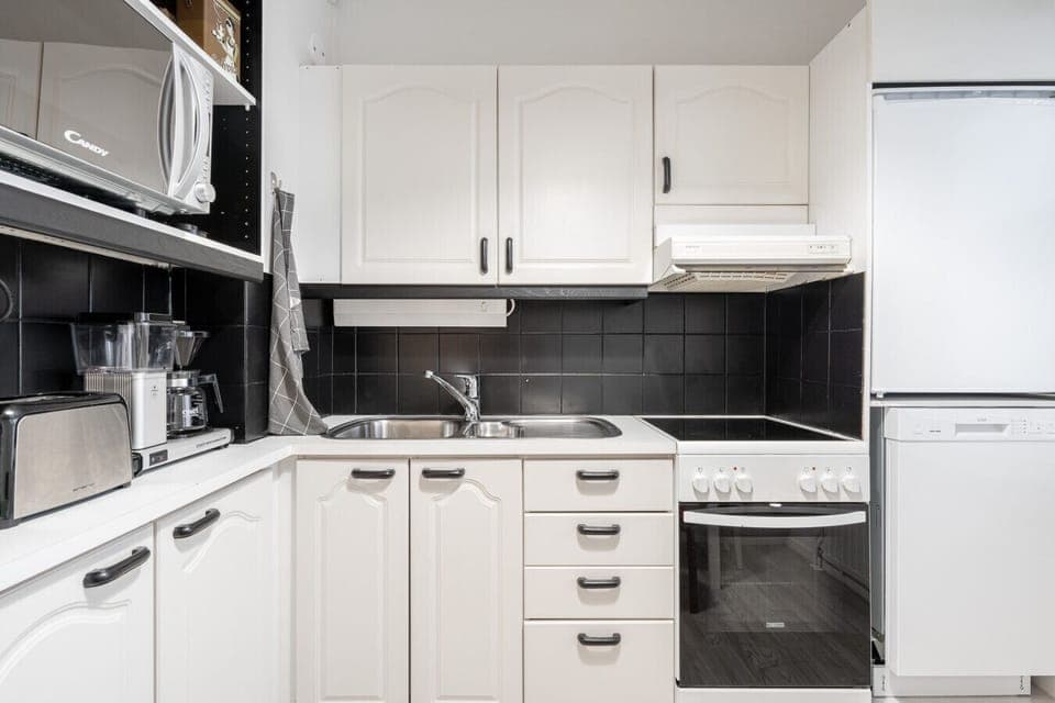 The kitchen features sleek cabinetry, quality cookware, and all the essential appliances—including a stove, oven, fridge, microwave, and kettle.
