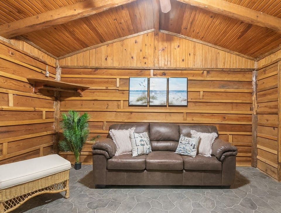 Cozy cabin living area with warm wooden walls and a comfortable leather sofa creating a relaxing atmosphere.