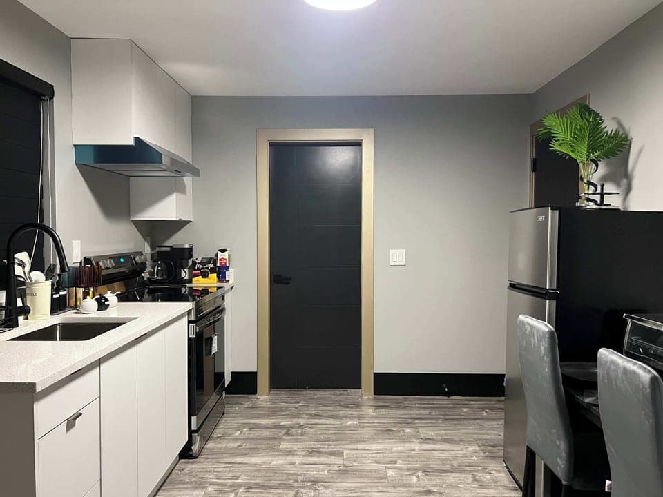 A clean, modern kitchen featuring stainless steel appliances, quartz countertops, and sleek white cabinetry, perfect for preparing anything from light breakfasts to full dinners.