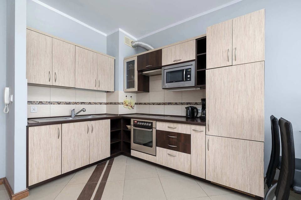 A modern kitchen with light-colored cabinets, an oven, and an induction stove.