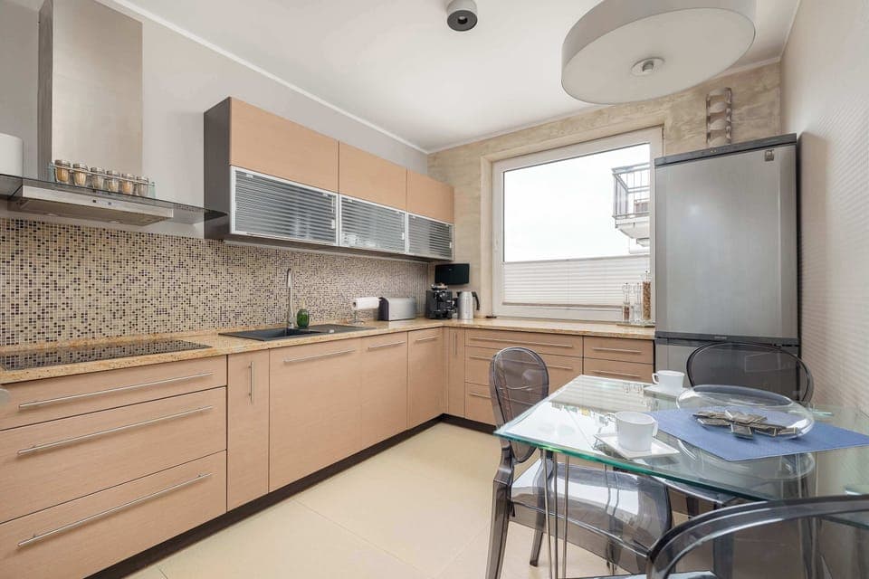 A fully equipped kitchen with wooden cabinets, a modern oven, and a stylish backsplash. A cozy dining area with a glass table and chairs adds to the convenience.