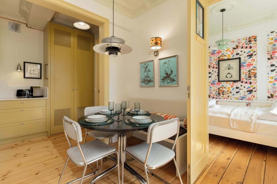 A modern living space combining the dining area and living room, lit with hanging lamps and large windows.