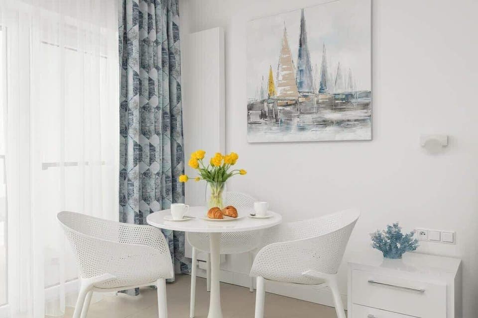 A small dining nook next to large windows, allowing plenty of natural light to flood the space. Ideal for enjoying a quiet morning coffee or intimate meal.