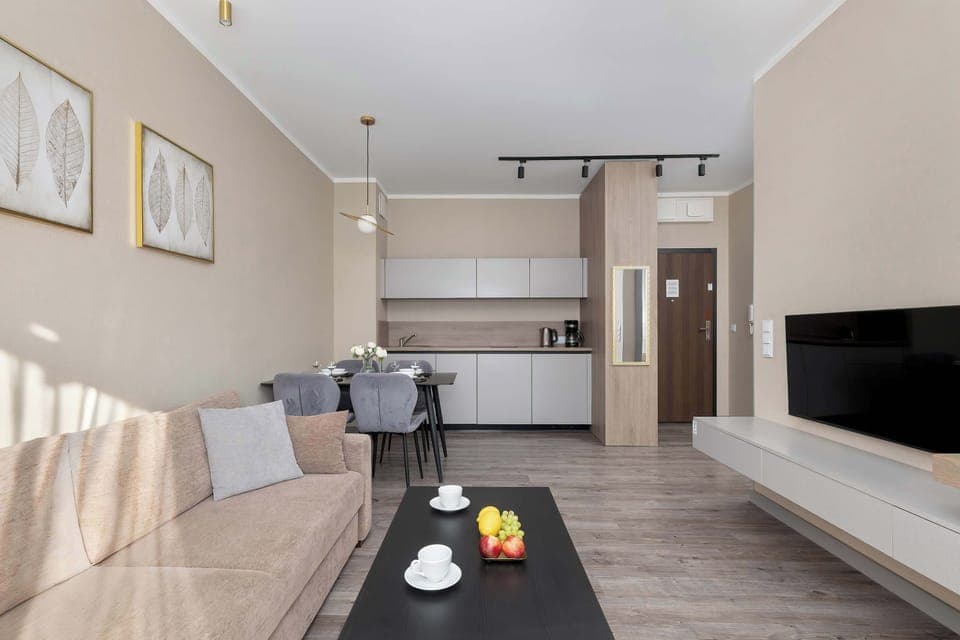 A spacious living room with a large sectional sofa and wall-mounted TV. Decorative accents and artwork enhance the elegant design.