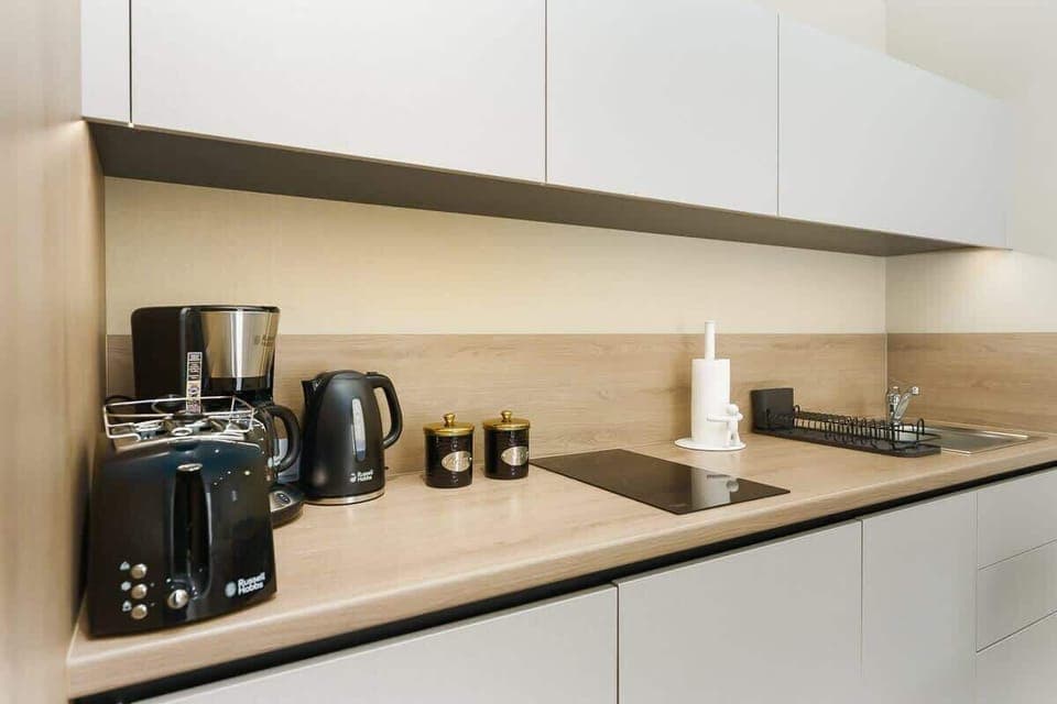 A modern kitchen countertop with a coffee machine, toaster, and kettle, emphasizing convenience and style.
