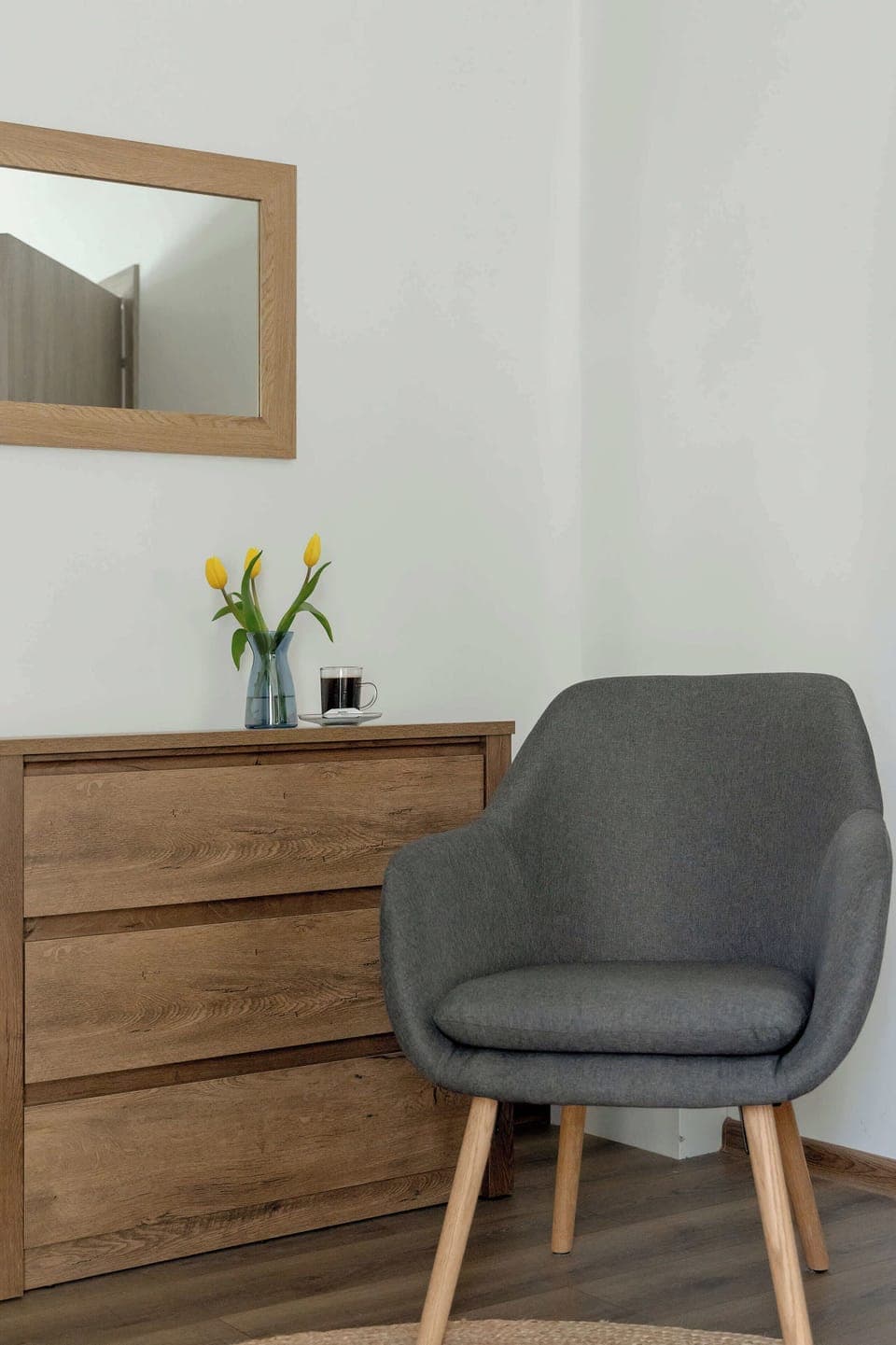 A small nook with a dresser and comfy chair offers a perfect spot for a moment of rest or morning routine.