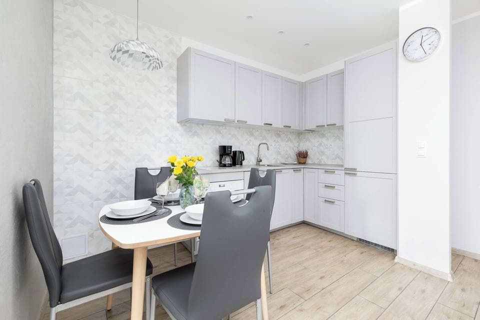 A bright and open dining space with a modern white kitchen featuring elegant finishes and ample storage.