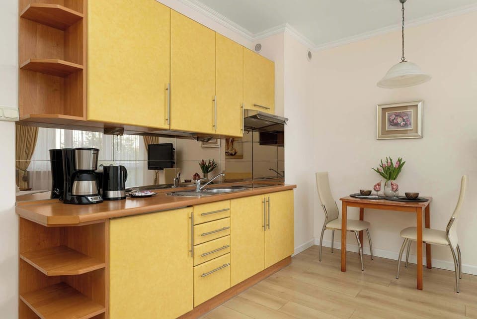 The modern kitchen in the studio with wooden cabinets, a full set of appliances, and a table against the wall combines functionality with aesthetics.