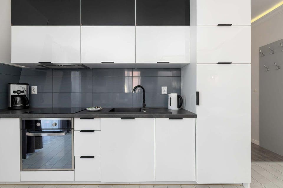 Modern kitchenette with white cabinetry and built-in appliances, integrated into the living area.