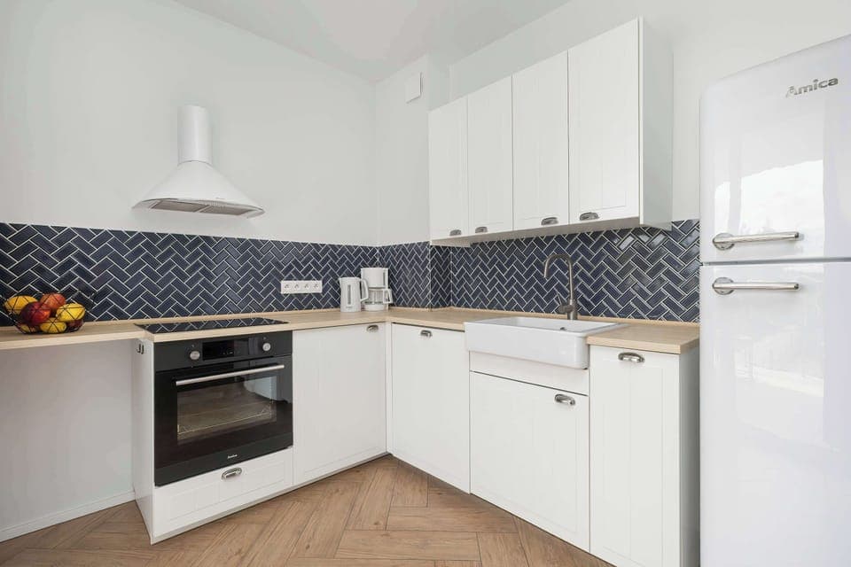 A second view of the kitchen area with modern white cabinetry and essential appliances. Bright and functional for everyday cooking.